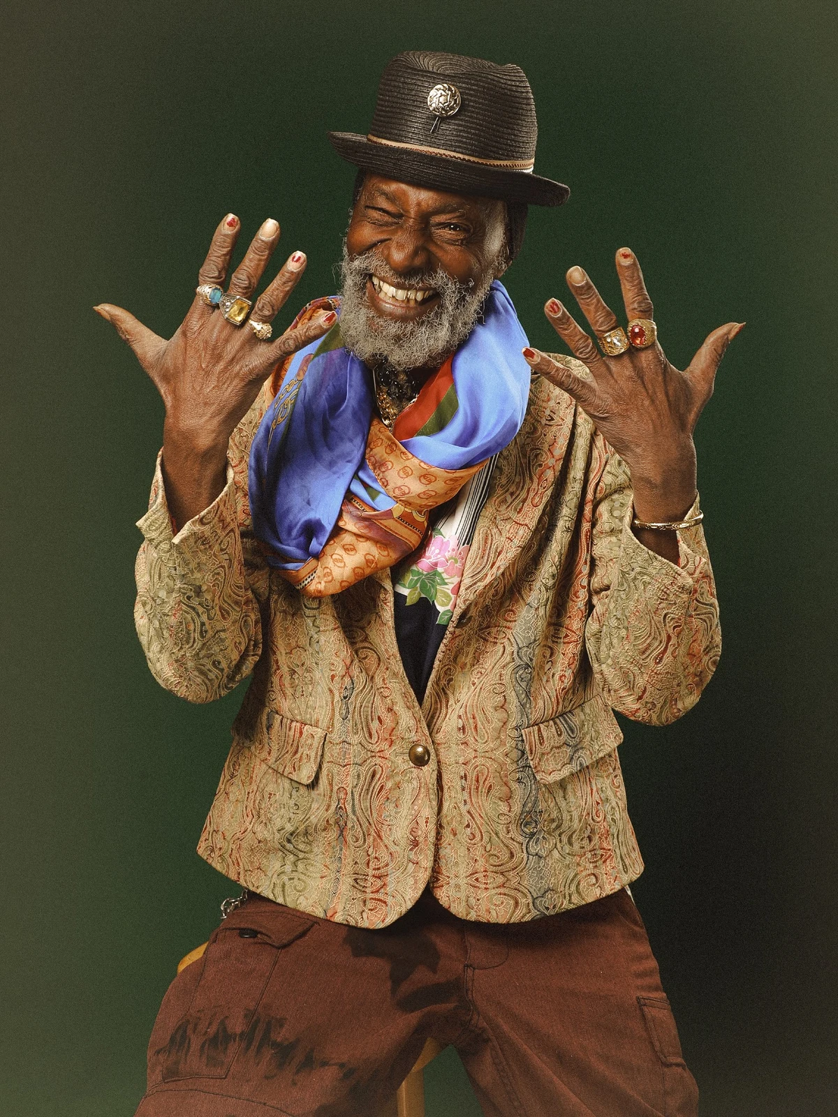 Izaba, TerraZen's host — studio portrait, hands raised, paisley jacket, vivid scarf